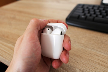 Man holding box with white headphones in office