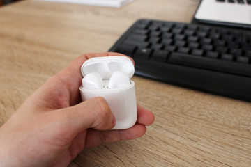 Man holding box with white headphones in office