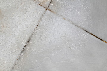 Bubbles soap detergent with scrubbing the bathroom floor dirt wet, Foam white bubble from shampoo washing on Tiled floor top view