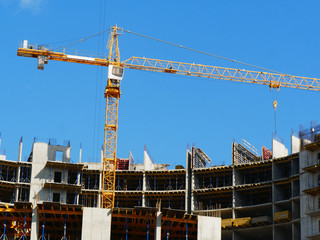 Construction crane near building under construction against blue sky. Construction site.