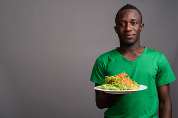 Young African man wearing green shirt against gray background