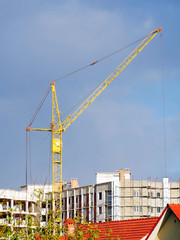 Construction crane near building under construction against blue sky. Construction site.