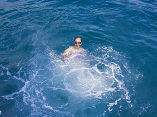 Happy beautiful girl in a sweemsuit and water-glasses splashing in the sea