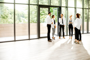 View on the modern office hall with a group of business people talking together near the window...