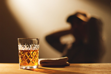 Glass of whiskey on a wooden table. Copy space. Nutrition background. Whiskey with a view of blurred man background.