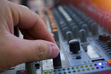 professional stage sound mixer closeup at sound engineer hand using audio mix slider working during concert performance.