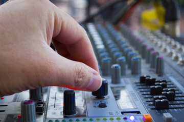 professional stage sound mixer closeup at sound engineer hand using audio mix slider working during concert performance.