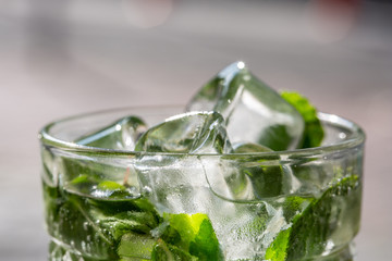 Twigs green mint in mojito with slices lime, ice cubes, straw, macro, texture