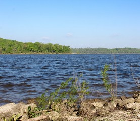 A view of the quiet lake over the rocks on the shore.