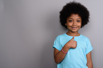Young cute African girl against gray background