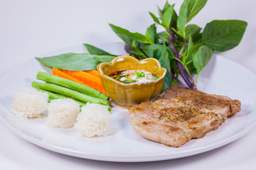 pork steak and vegetable served on  white dish with white background