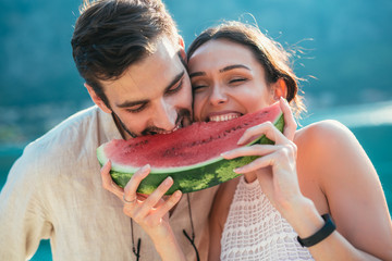 Cheerful couple holding slices of watermelon