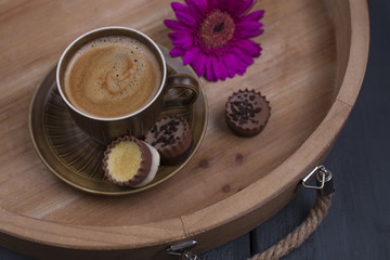 Delicious milk chocolate, a bouquet of fresh flowers and a morning aromatic coffee. Black wooden background, free space for text. Copy space.