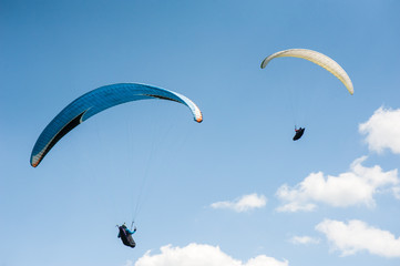 Two paragliders flying in the blue sky against the background of clouds. Paragliding in the sky on a sunny day.