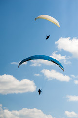 Two paragliders flying in the blue sky against the background of clouds. Paragliding in the sky on...