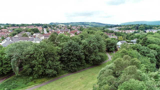 Low level aerial image over a rural village surrounded by woodland. 