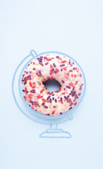 Sweet holiday / Creative concept photo of donut with illustrated globe world map on blue background.