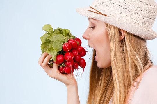 Happy woman biting radish