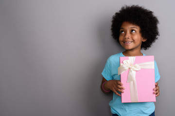 Young cute African girl against gray background