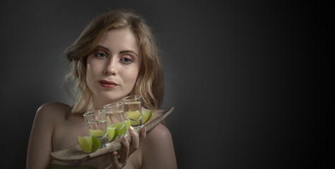 Beautiful woman with glasses of tequila and lime slices.