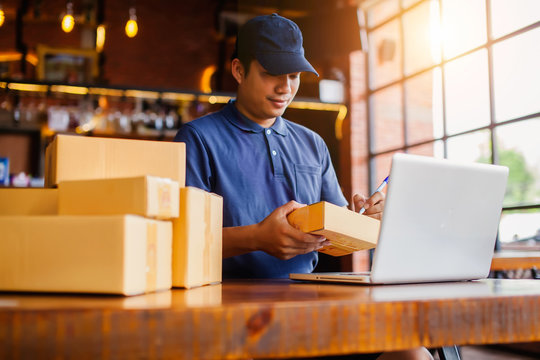 Asia Delivery Man Are Holding A Cardboard Box Delivery To His Customer.Delivery Man Are Checking To His Customer,The Seller Prepares The Delivery Box For The Customer, Online Sales, Or Ecommerce.