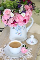 Kaffeetasse und Blumenstrauß in der Teekanne