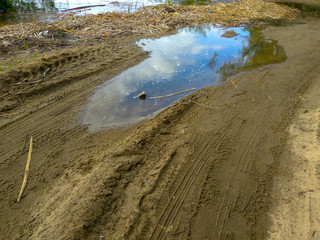 Country road with puddle and straw