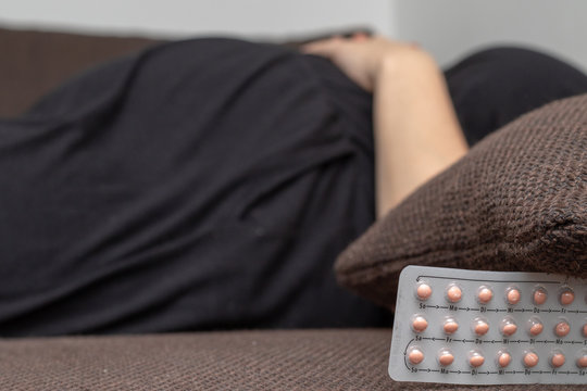 Contraception with pink anti baby pills in front of a pregnant woman