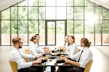 Group of business people sitting together during a business lunch at the modern restaurant with big...