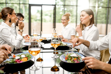 Business people dressed in white shirts having fun sitting together during a business lunch with delicious meals and wine in the modern restaurant