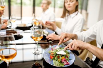 Businessman eating delicious salad during a business lunch at the restaurant, close-up view