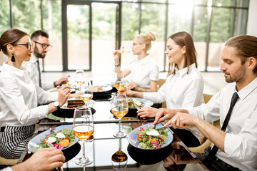 Business people dressed in white shirts having fun sitting together during a business lunch with delicious meals and wine in the modern restaurant