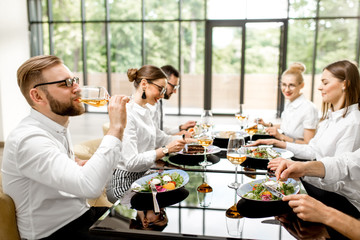 Business people dressed in white shirts sitting together during a business lunch with delicious meals and wine in the modern restaurant