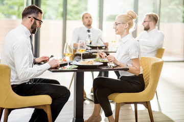 Business people having lunch with delicious meals sitting in pairs at the modern restaurant