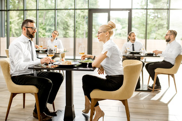 Business people having lunch with delicious meals sitting in pairs at the modern restaurant