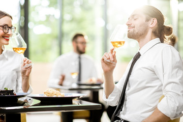 Beautiful couple enjoying wine sitting during a business lunch at the bright restaurant