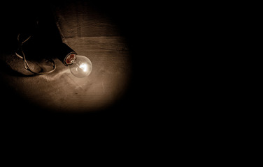 The light bulb in the dark is on dark black background