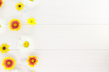 White daisies and garden flowers on a white wooden table. The flowers are arranged side, empty space left on the other side.