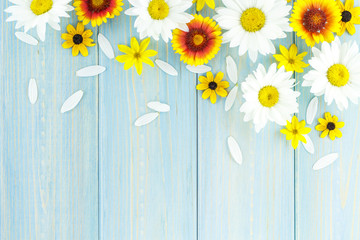 White daisies and garden flowers on a light blue worn wooden table. The flowers are arranged in the upper part, the empty space left below.