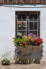 Fototapeta na wymiar Holzfenster mit Blumen am Bauernhof