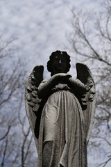 Sculpture of an angel who looks down to the people who visit a cemetery
