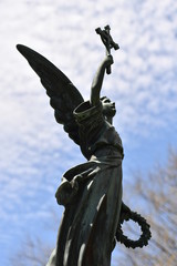 culpture of an angel who raises the christian cross in the air