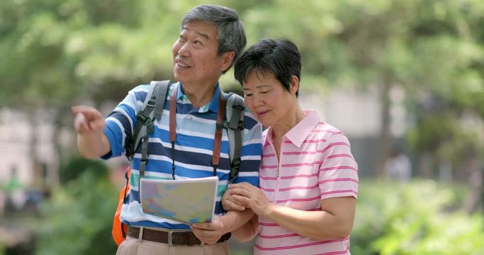 Asian old couple go travel and look at the map together at outdoor
