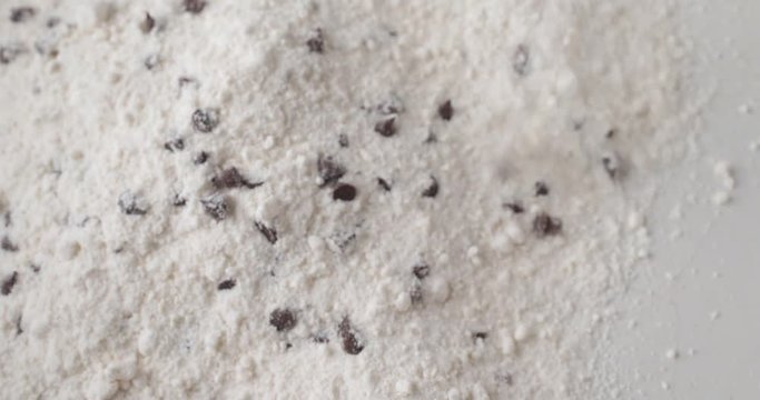 Close video of dry clumpy chocolate chip muffin mix being poured into an old ceramic bowl.