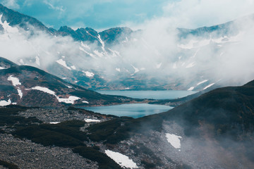 Two large lakes surrounded by mountains covered with snow in fog