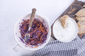 Salad from fresh cabbage and carrots, fresh bread and yogurt with cucumber. Spring vegetables and white sauce. Lunch is vegetarian. Tasty and healthy food. Copy space.