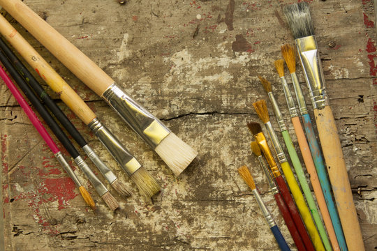 different size paint brushes on a rustic wood table, artist workshop