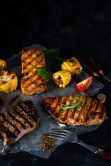 Three types of grilled meats with vegetables and spices on paper