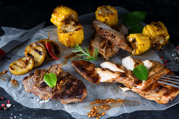 chopped chicken meat, pork and beef with corn, spices on paper on a dark background