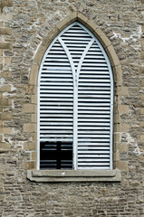 A shuttered stone church tower window